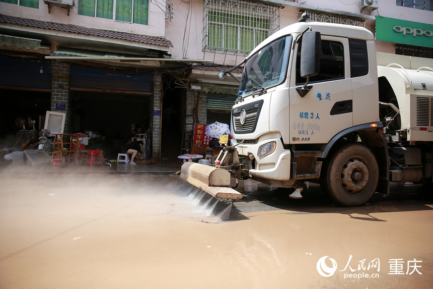 環(huán)衛(wèi)車輛沖刷仁沙鎮(zhèn)場鎮(zhèn)路面的淤泥。人民網(wǎng)記者 劉政寧攝